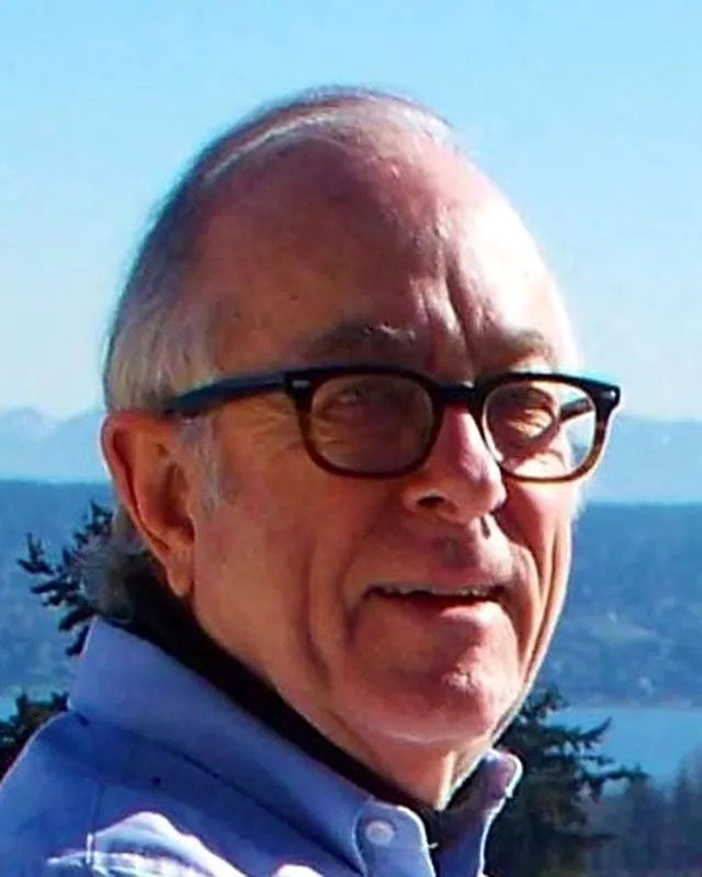 John G. Cramer outdoors, with water and mountains behind him