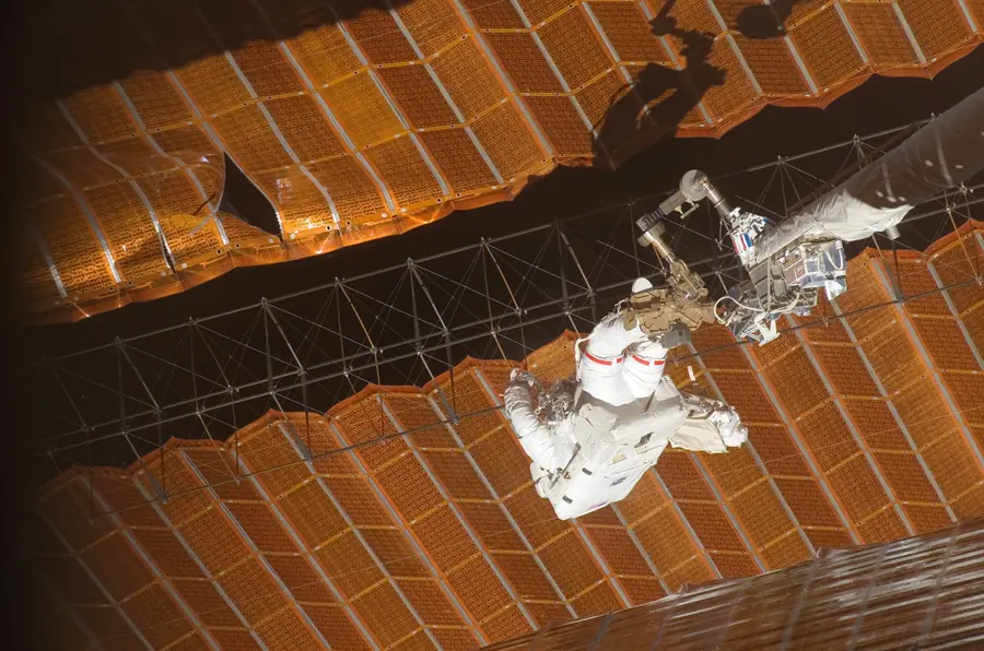 Astronaut Scott Parazynski on the end of a boom, repairing a solar array outside the International Space Station